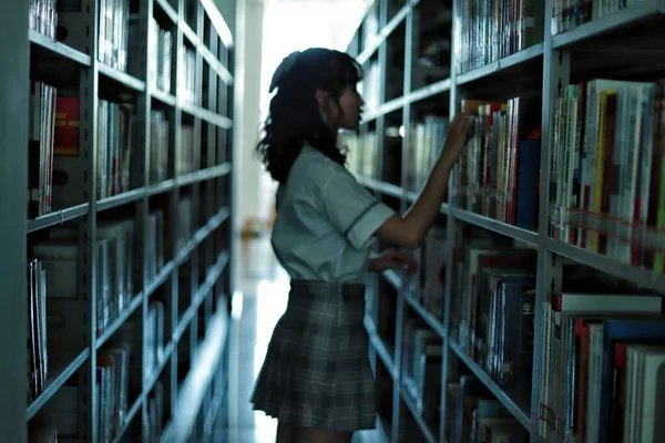 young woman in library with books and book