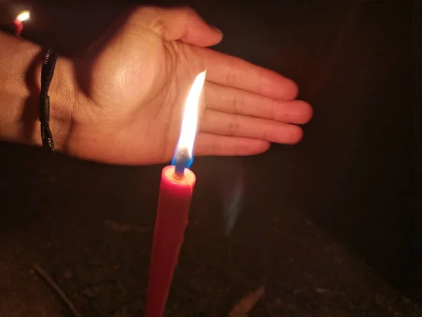 close up of a burning candle in a hand