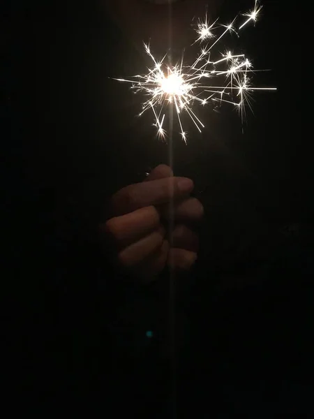 sparkler in hand on black background