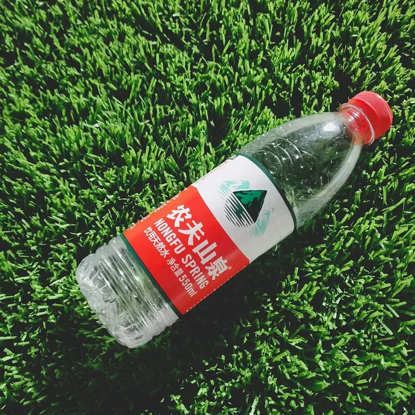 a green plastic bottle with a red liquid on a white background