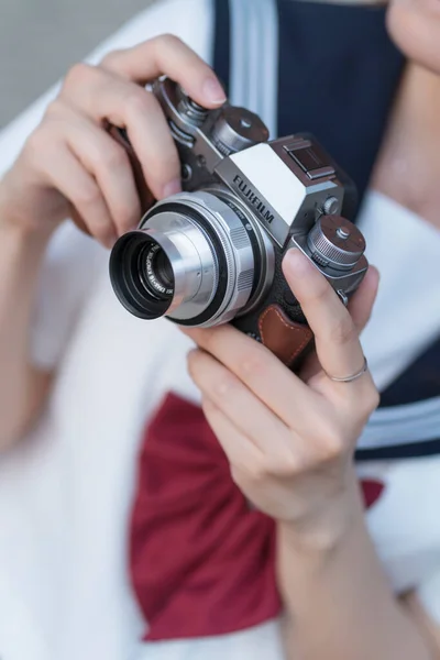 close-up of a young woman holding a camera and taking a photo of a retro film.