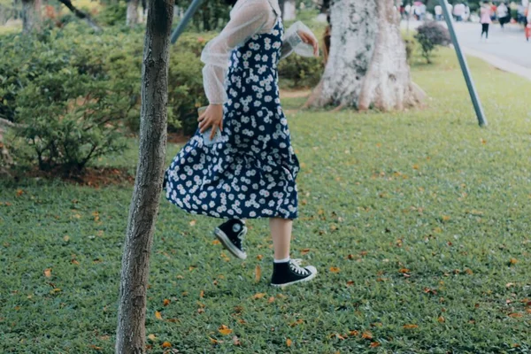 young woman in a dress with a bag in the park