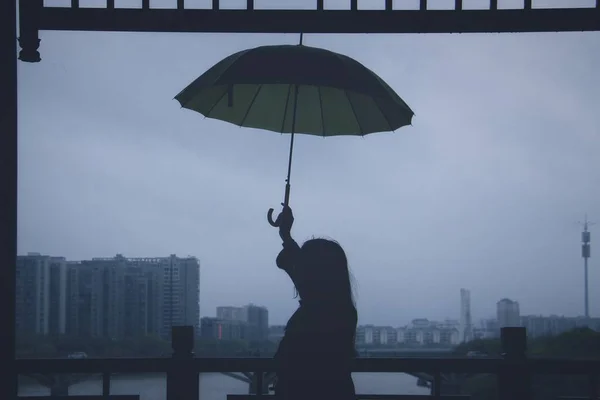 silhouette of a man with umbrella and rain drops on the background of the city