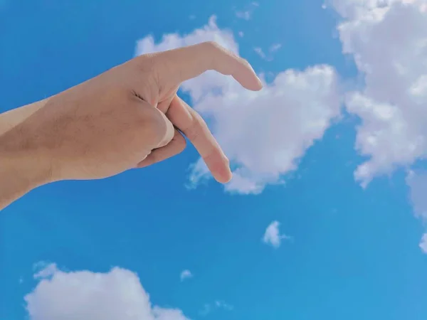 hand holding a blue sky with clouds
