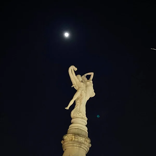 statue of a woman in the night sky