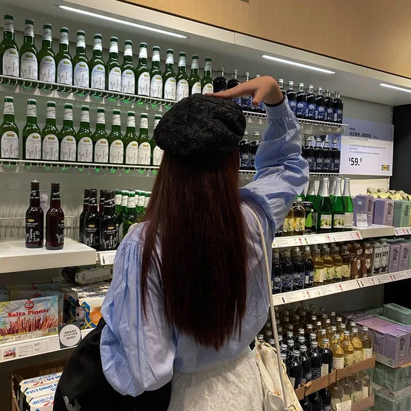 young woman with wine bottles in supermarket