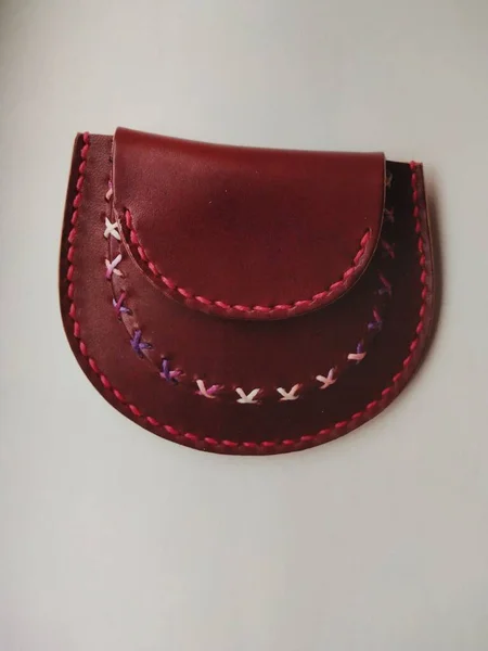 a closeup shot of a leather purse with a red buckle on a white background