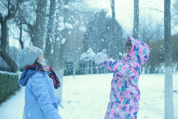 mother and daughter playing with snow in the winter park