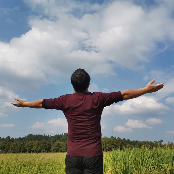 man in a blue shirt and a white t-shirts on a background of clouds