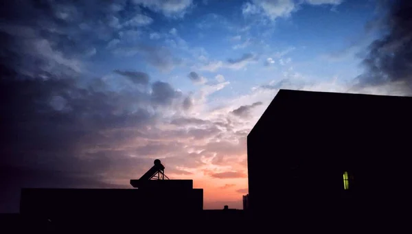 silhouette of a man with a backpack on the roof of the building