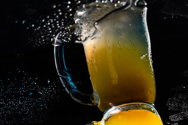 glass of beer with ice cubes on black background