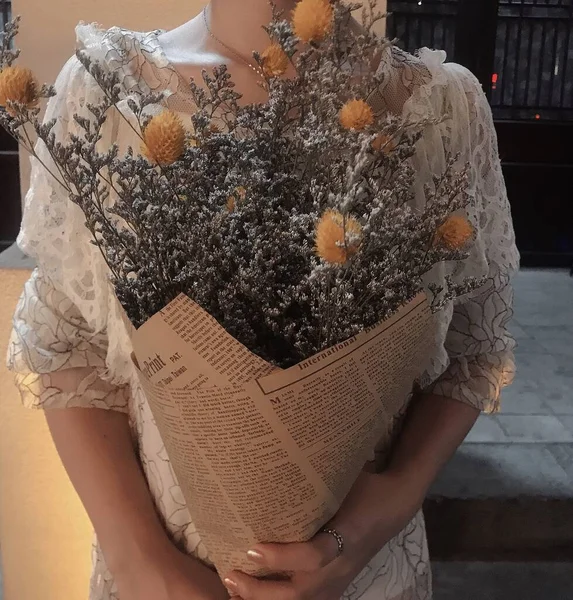 woman in a white shirt with a bag of flowers