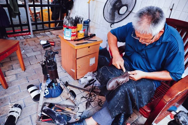 old man working with a sewing machine