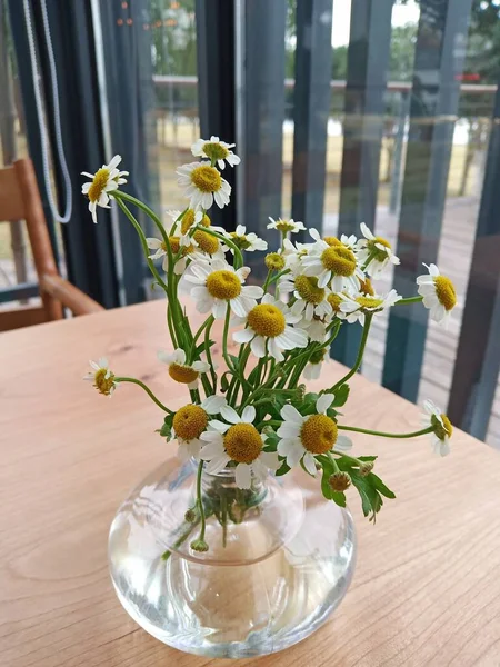 beautiful flowers in a glass vase on a wooden table