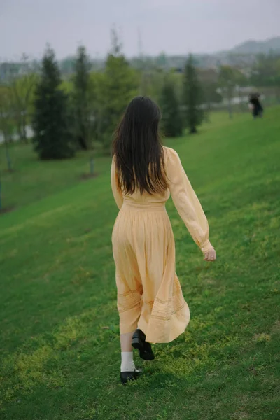 young woman in a green dress with a bag in the park