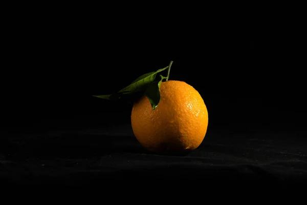 orange with leaves on black background