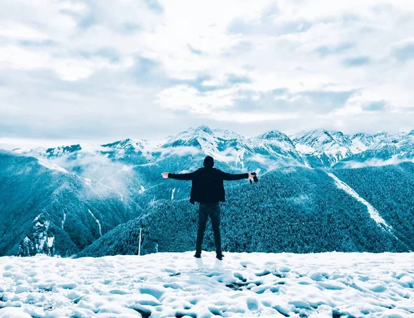 man in a jacket with a backpack on the top of the mountain