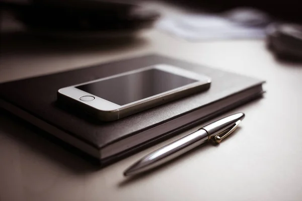 black smartphone with pen and mobile phone on wooden table
