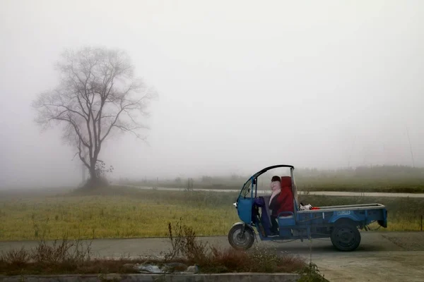 a man in a field with a tractor in the fog
