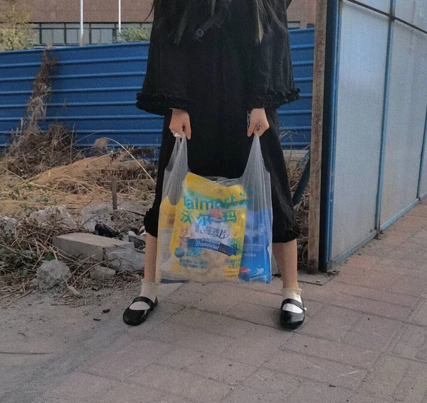 young woman in a black dress with a bag