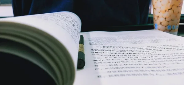 close up of a book with a pen and a bible