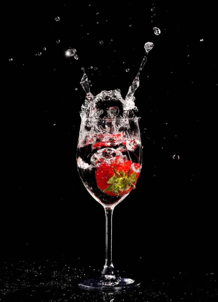 red wine in glass with splash on black background