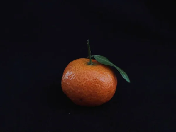orange with green leaves on black background