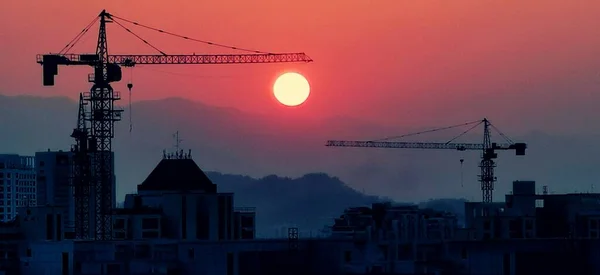 silhouette of a building cranes on the background of the city