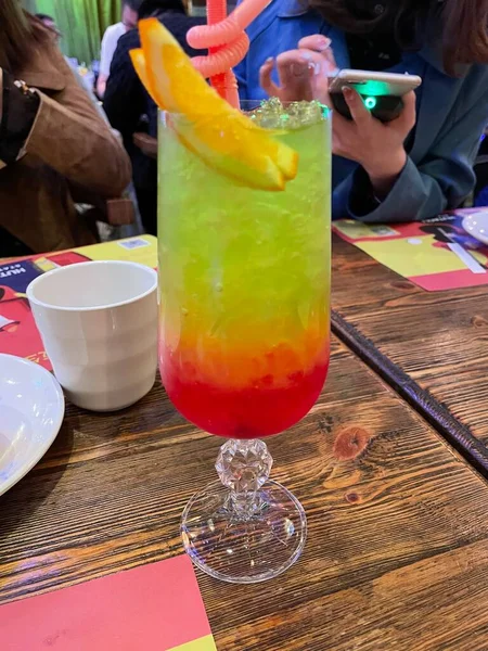 a glass of cocktail with a drink and a straw