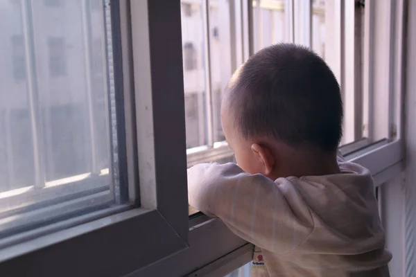 little boy looking through window in the room