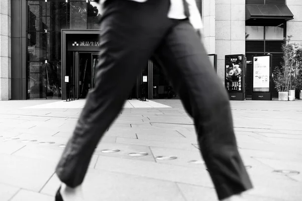 black and white photo of a man walking in the city