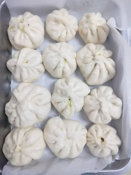 white and gray raw dumplings on a wooden table.