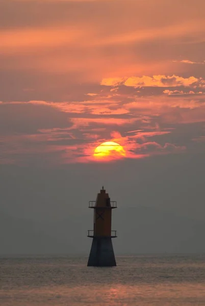 lighthouse at sunset, the sea, the sun sets, the sky and the clouds