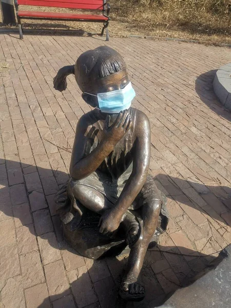 a man in a mask and a protective face masks on a bench in the city