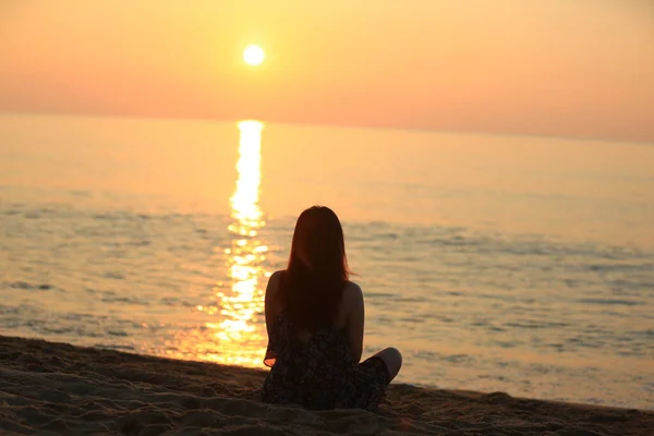 silhouette of a woman sitting on the beach at sunset