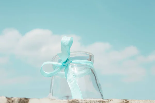 white gift box with blue ribbon on the beach