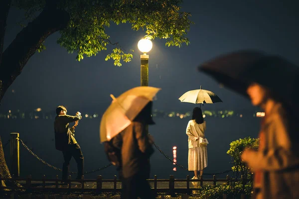 a man and a woman in a rain umbrella on a background of a rainy night