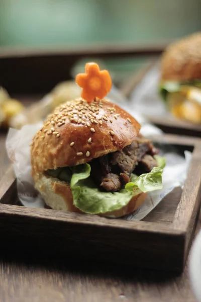 delicious burger with chicken, cheese and lettuce on wooden table