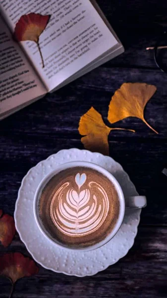 cup of coffee with a book on a wooden background