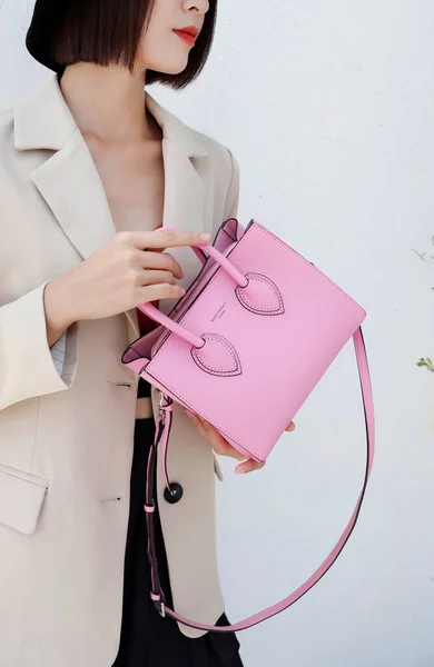 beautiful young woman with pink bag and handbag