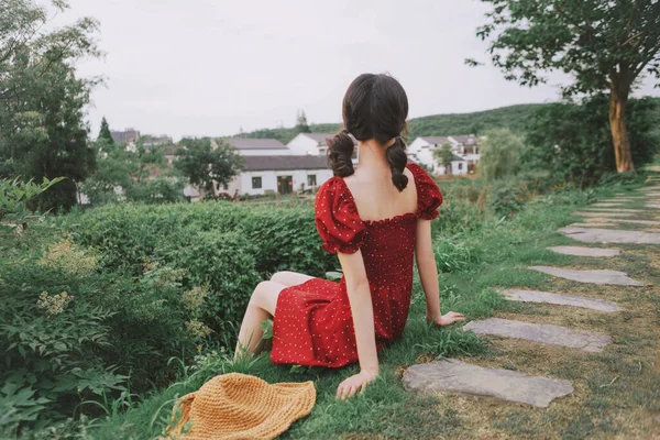 young woman in a red dress with a bag in the park