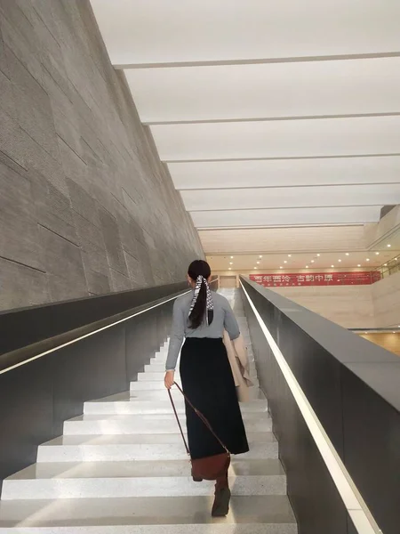 young woman in suit walking on stairs