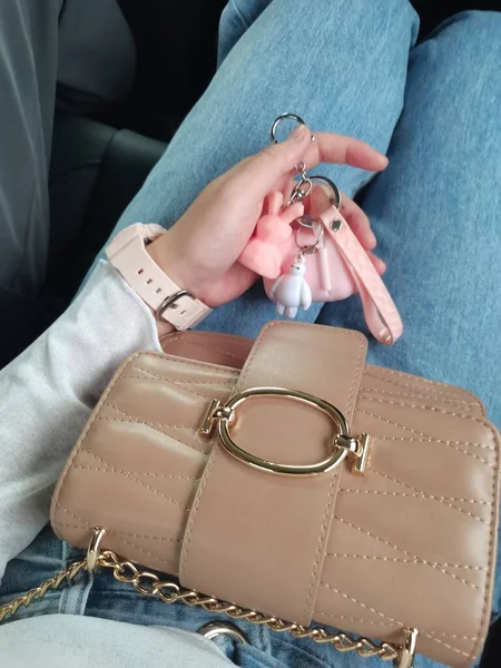 woman\'s hands with a leather bag and a chain on a black background