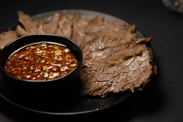 beef steak with sauce and spices on a black background