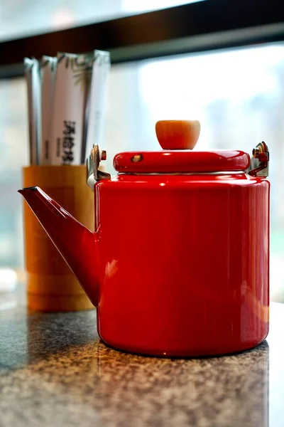 red kettle with a lid and a cup of tea