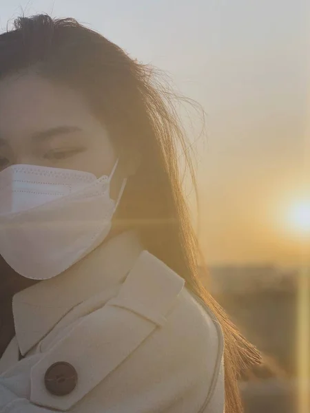 woman in a protective mask and a white shirt and a scarf on the background of the city.
