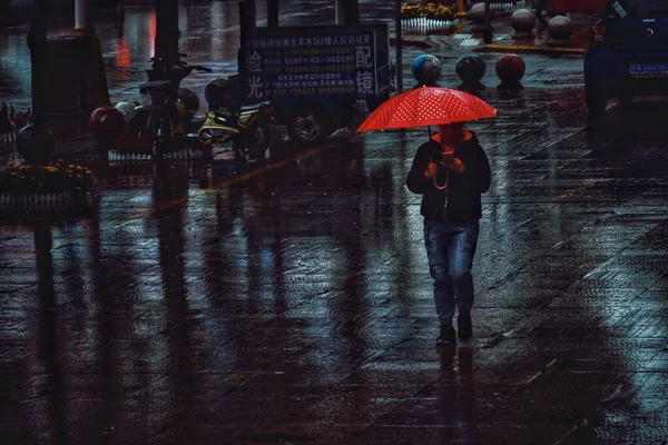 man in a black jacket and a raincoat walking in the city