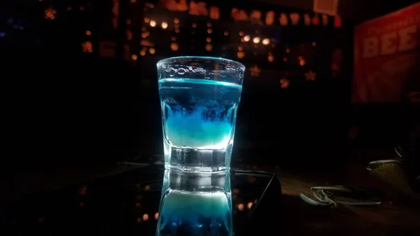 a glass of cocktail with a candle on the background of a bar counter