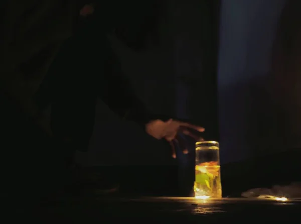 man pouring whiskey into glass with a candle in the background
