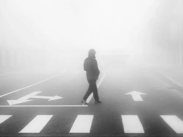 silhouette of a man with a white arrow on the road